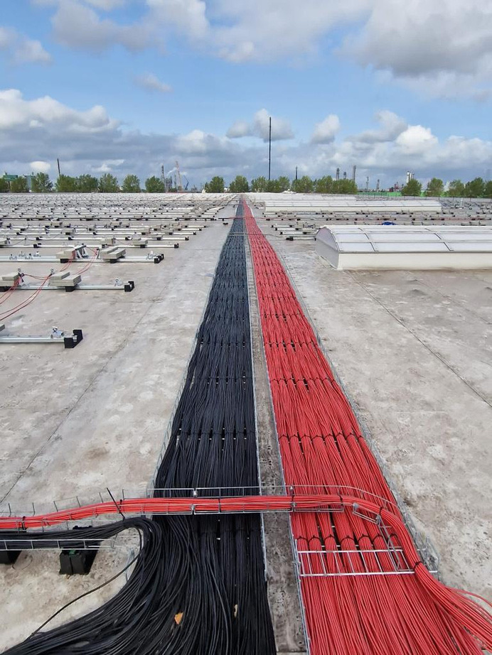 Red and black DC cable runs across a large rooftop solar project